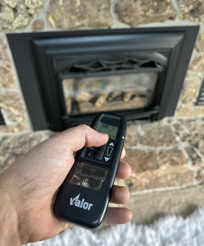 A hand holds a black remote control displaying 